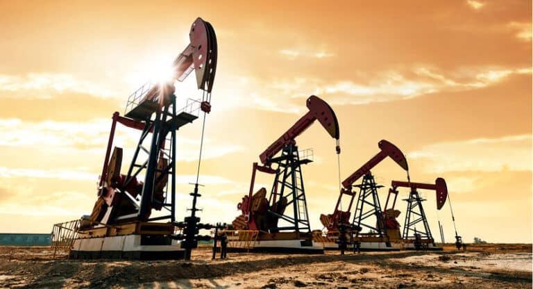 Oil & Gas Manufacturing Oil pumps silhouetted against a vibrant sunset in a desert landscape.