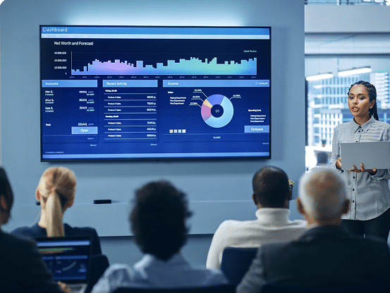 Business presentation in a modern office with a person showing financial data on a large screen, including charts, graphs, and net worth metrics.