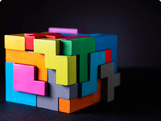 3D cube puzzle made of brightly colored interlocking wooden blocks against a dark background.