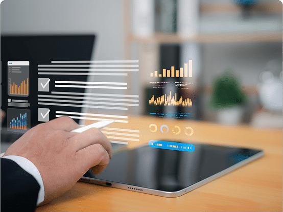 A person uses a stylus on a tablet at a wooden desk, with holographic charts and data visualizations projected above the device.