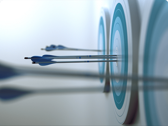 Close-up of arrows hitting the bullseye on multiple archery targets aligned in a row, with a blurred background.