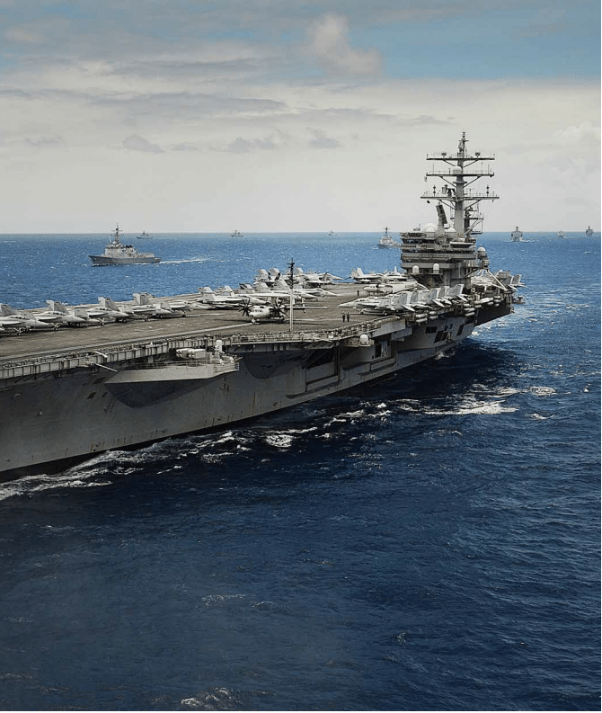 Aircraft carrier with fighter jets and escort ships at sea