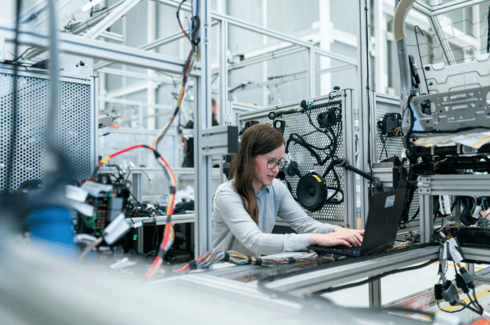 Person working on a laptop in a high-tech industrial workspace