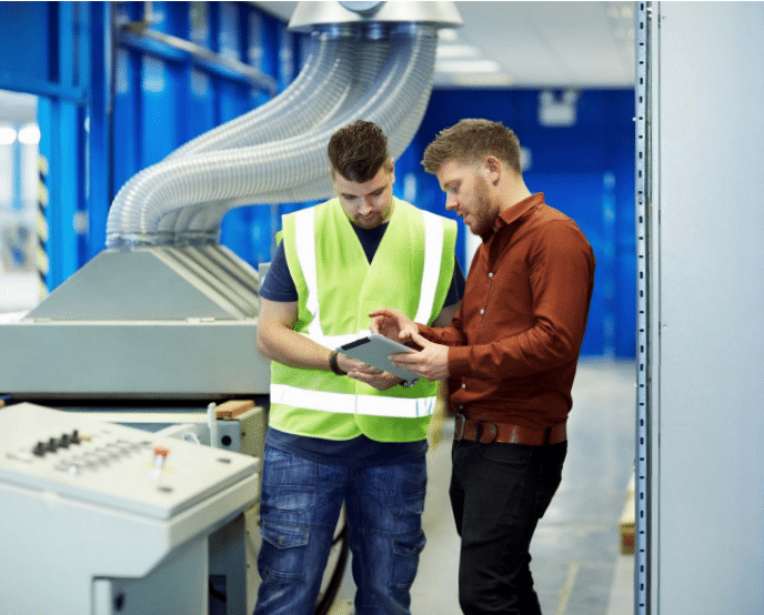 Two people reviewing data on a tablet in an industrial setting